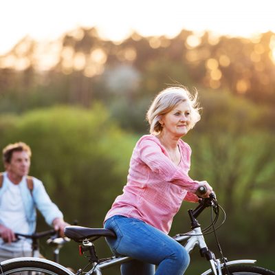Beautiful senior couple with bicycles outside in spring nature cycling.