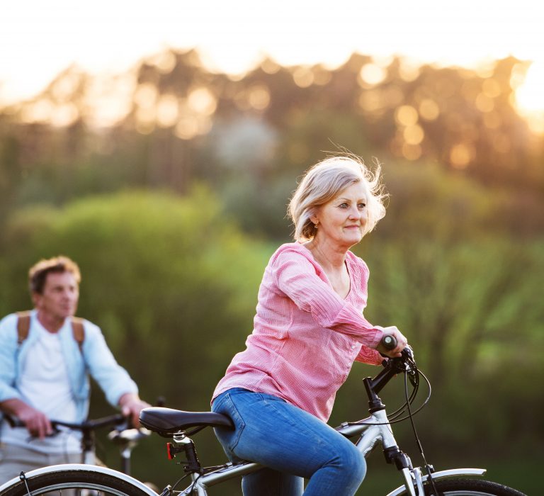 Beautiful senior couple with bicycles outside in spring nature cycling.